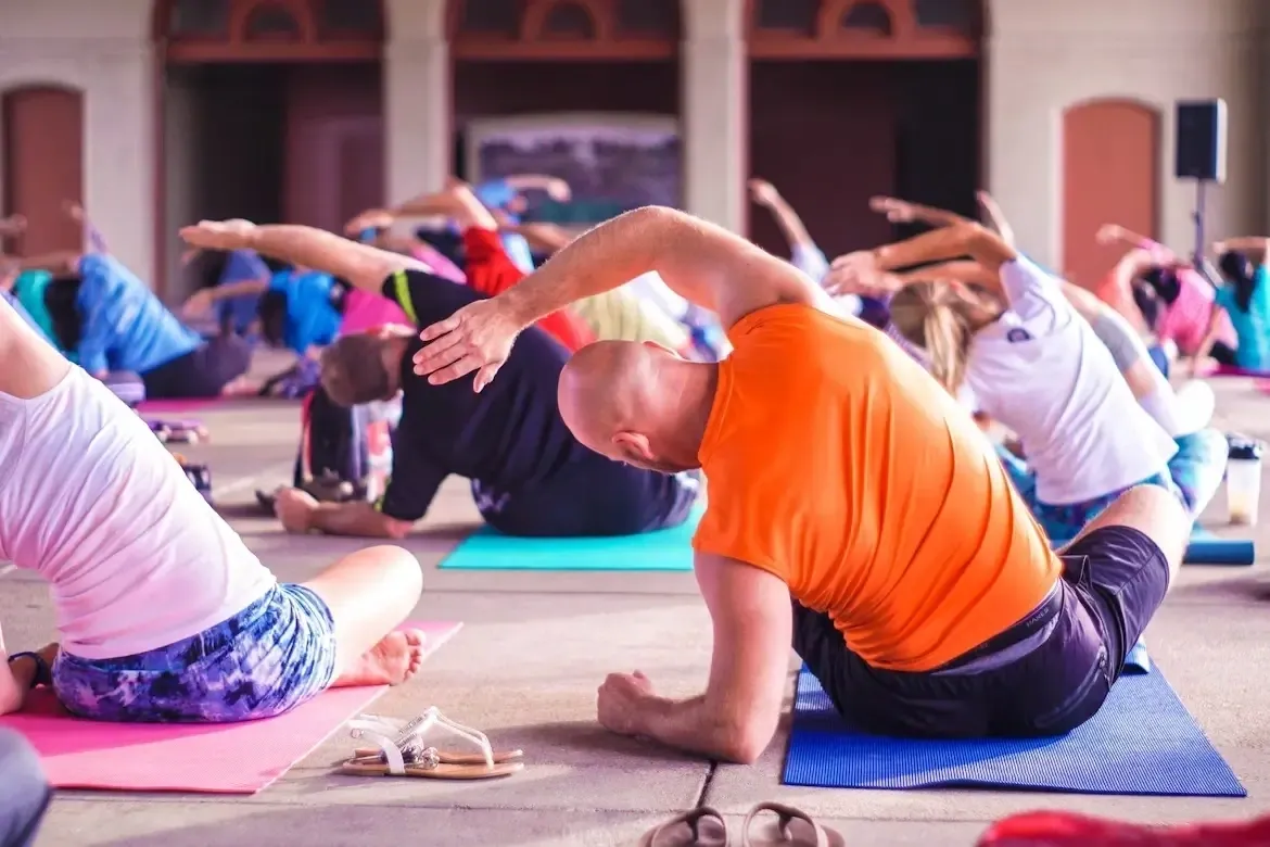 Group yoga class exercising outdoors with instructor